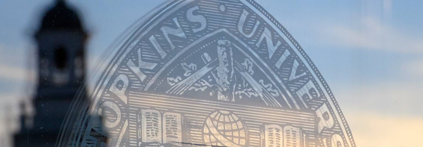 University seal in glass with campus tower seen in adjacent reflection