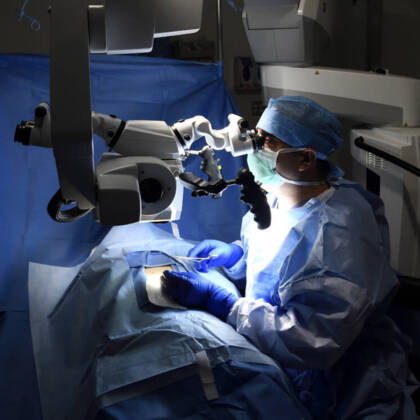A surgeon in blue scrubs performs a surgical procedure